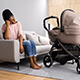 A woman sitting on a couch while looking at a baby stroller.