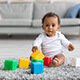 A baby sitting on the floor and playing with building blocks.