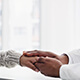 A doctor consoles a patient by holding their hand.