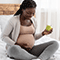 Pregnant woman holding apple and looking at her belly