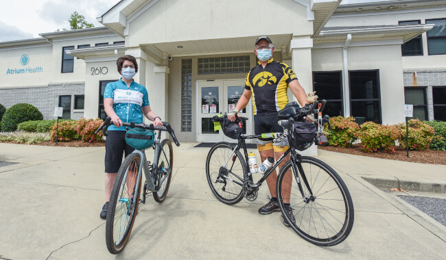 Deborah Bradley, MD (left), standing next to Ron Wasek, prostate cancer patient, both standing beside their bicycles.