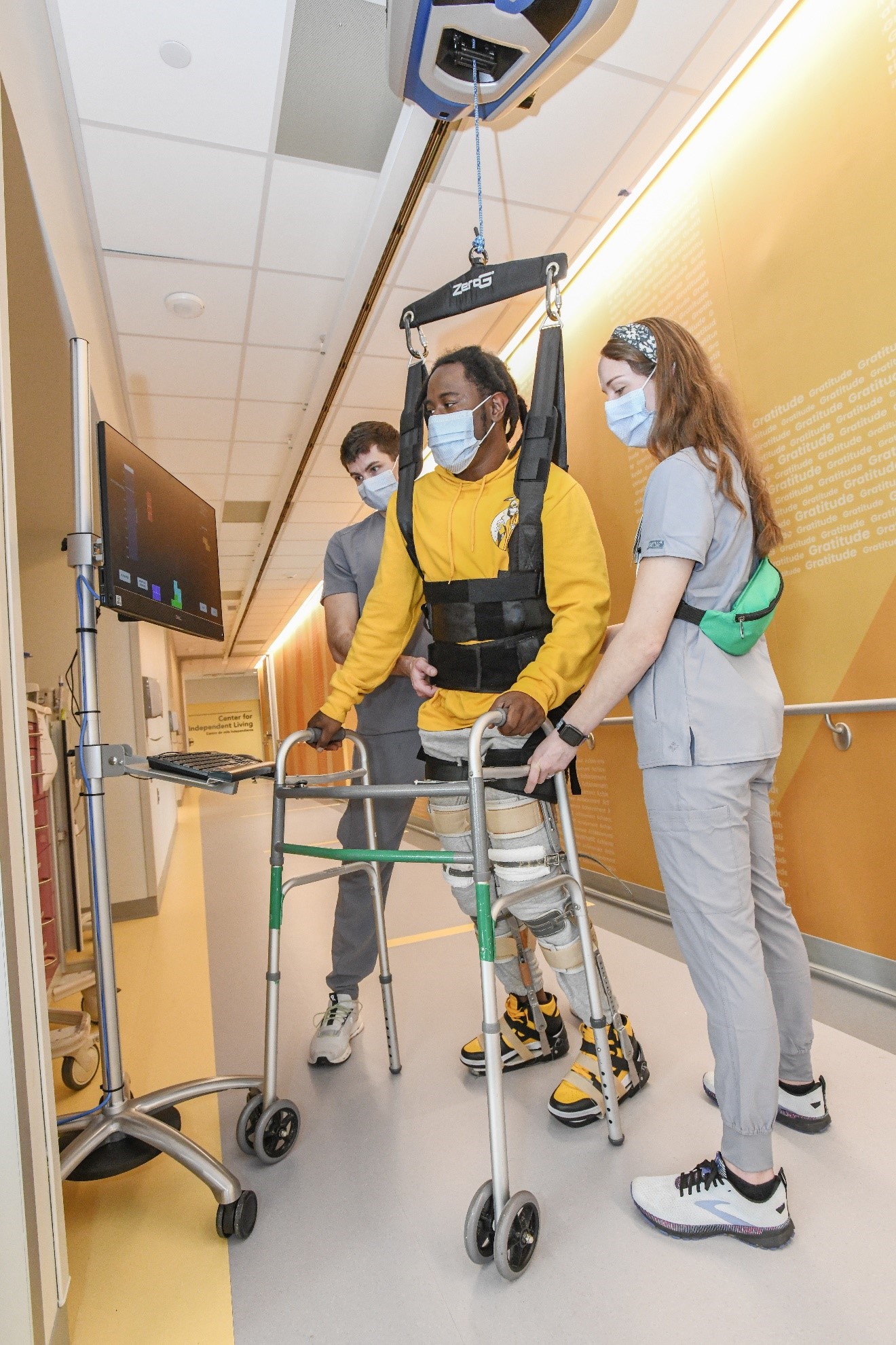 Man standing, assisted by Neurologic Physical Therapists and specialized equipment