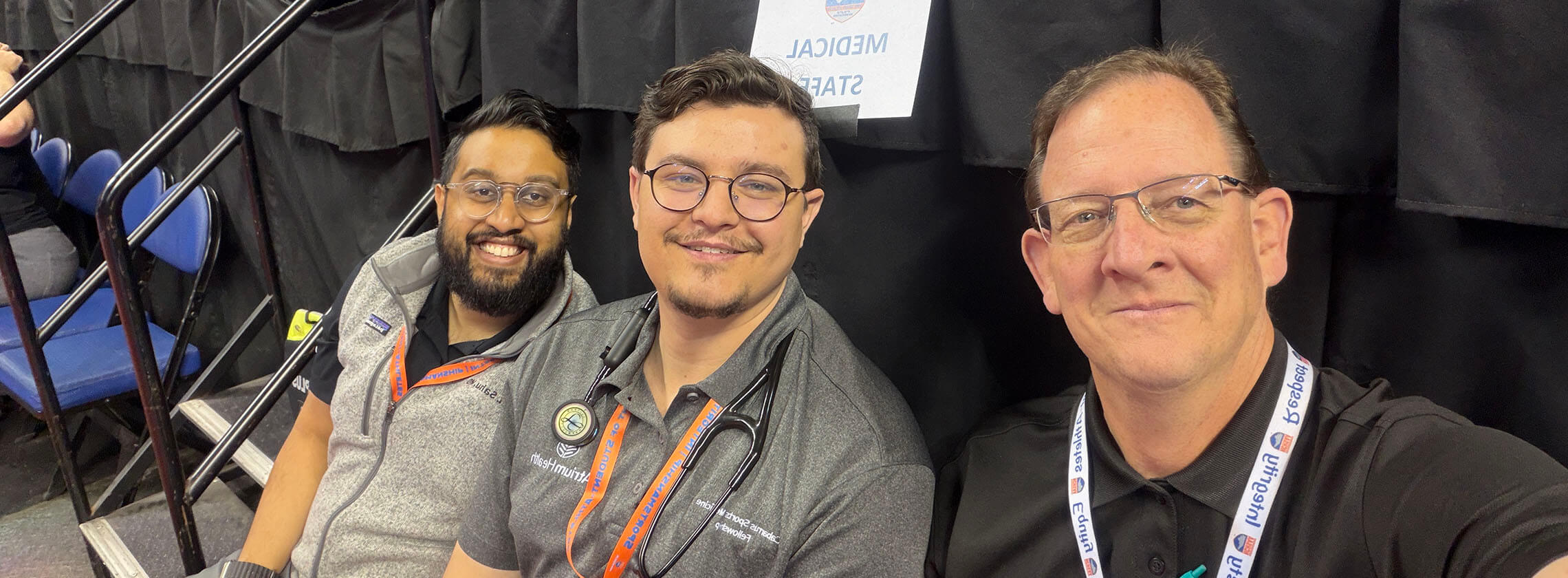 Three men sitting together at a sporting event.