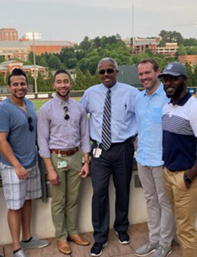 5 men in casual and formal attire standing together.