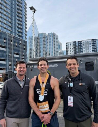 Three men standing together outside in a city.