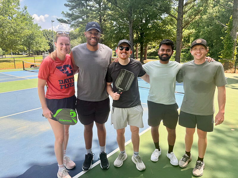 A group of men and women in athletic shorts and t-shirts standing together outside.