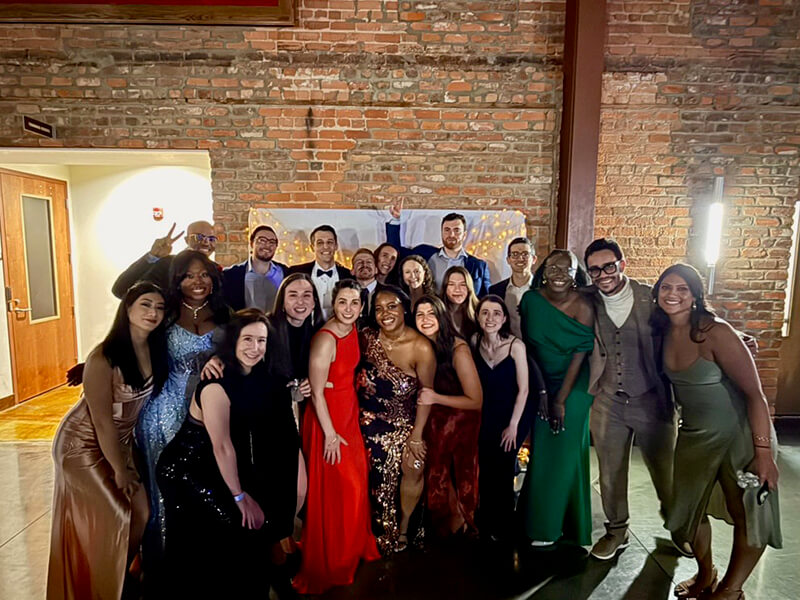 A large group of men and women in formal attire standing together for a photo.