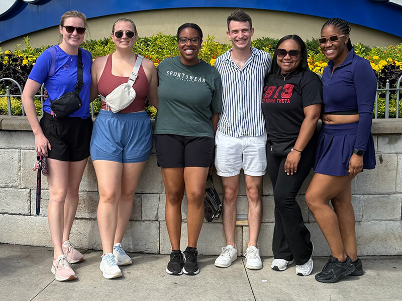 Six men and women standing together outside for a photo.