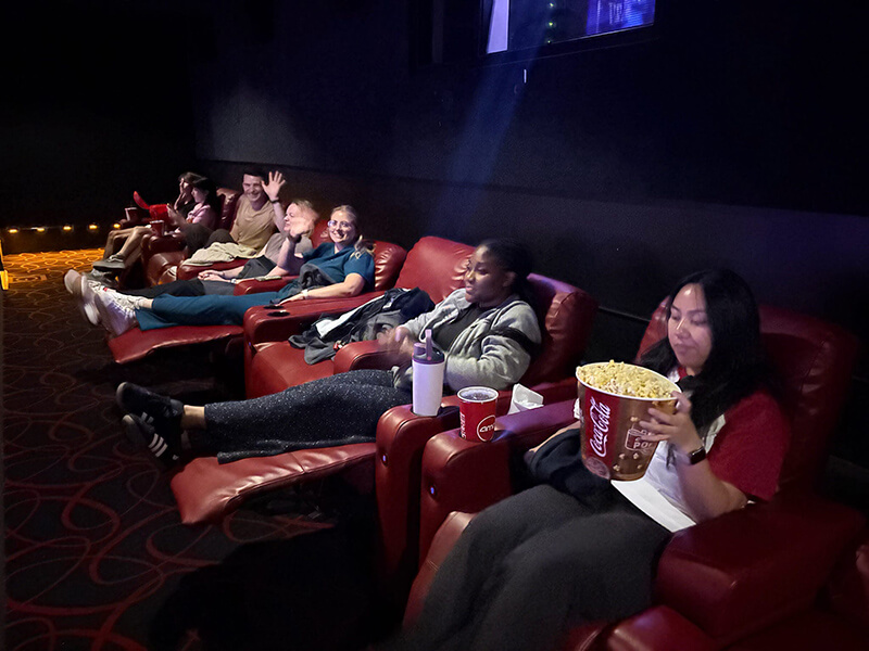 A group of men and women sitting in a movie theater eating popcorn and other snacks.