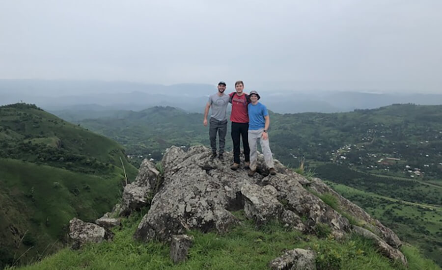 A trio standing on top of a mountain.