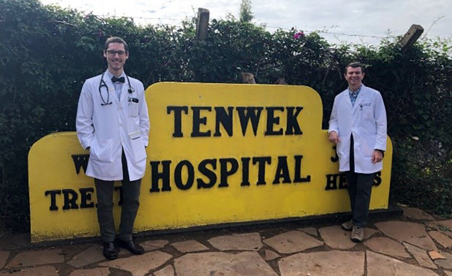 A duo standing in front of a medical sign.