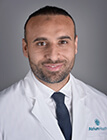 A headshot of a medical professional wearing a white lab coat.