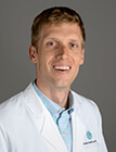 A man wearing a white lab coat smiling at the camera.