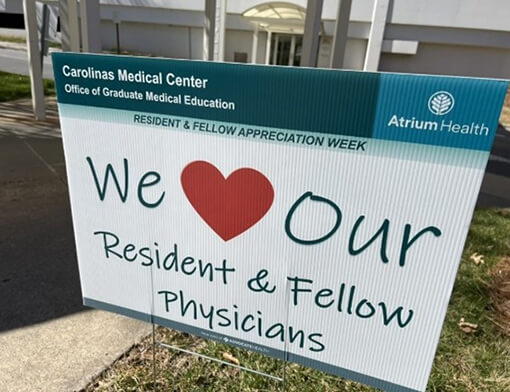 An outdoor sign that says "We love our resident and Fellow physicians".