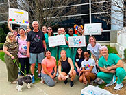 A group of colleagues and friends together with signs wishing a coworker a happy retirement.