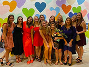 A group of people posing in front of a background with multiple hearts.