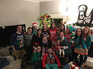 Friends and colleagues in Christmas sweaters posing for a photo.