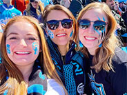 Three women smiling while dressed in sports gear.