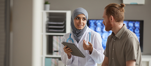 Provider and patient having conversation. Provider holds a tablet device. 
