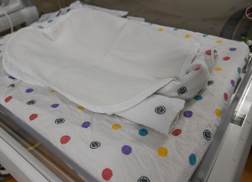 AN NICU bed adorned with polka-dotted sheets.
