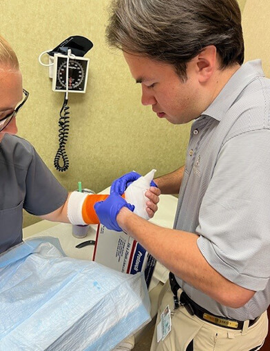 A medical professional helping apply a cast/wrap to the wrist area of a patient.