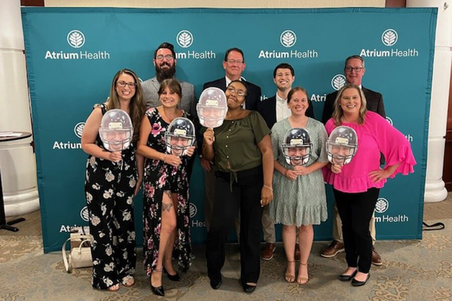 A large group of men and women standing in front of a photo backdrop.