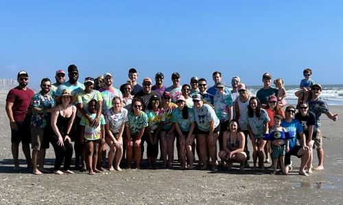 Urology Residents at the beach smiling and waving.