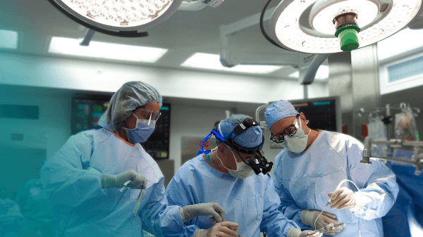 Three surgeons working on a patient.