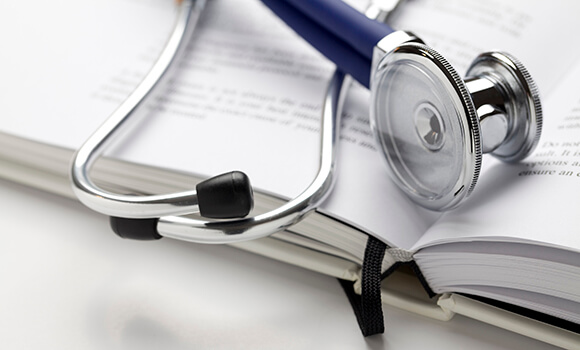 A blue stethoscope laying on a book.