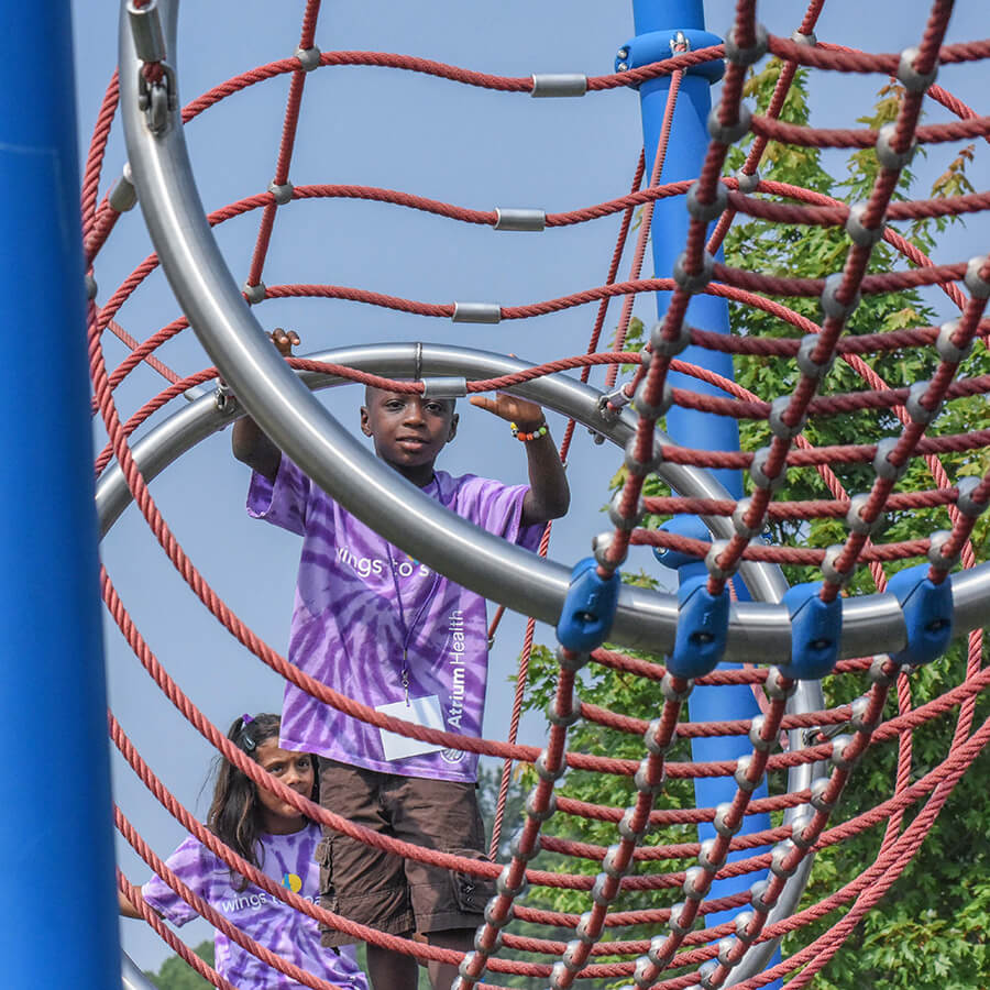 A young child walking across a cargo net.