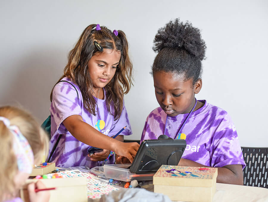 Two young children sitting at a table with arts and crafts.