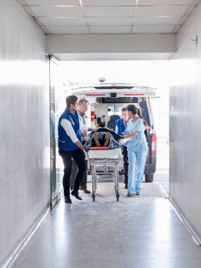 EMTs bringing in patient on stretcher into hospital from ambulance