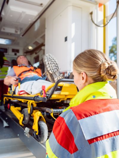 Female EMT taking care of male patient on stretcher coming out of ambulance
