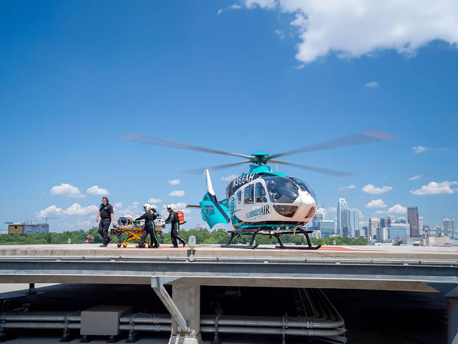 A group of medical personnel prepare to board a helicopter resting on a helipad.