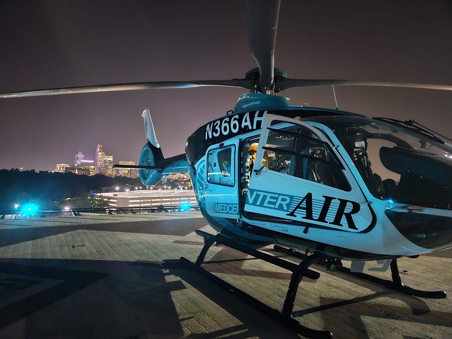 A teal, blue and white helicopter parked on a helipad.