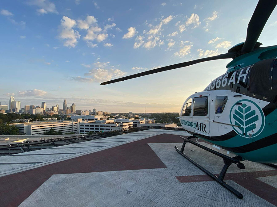 A teal, blue and white helicopter parked on a helipad.
