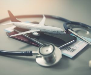 Airline ticket beneath airplane model with stethoscope