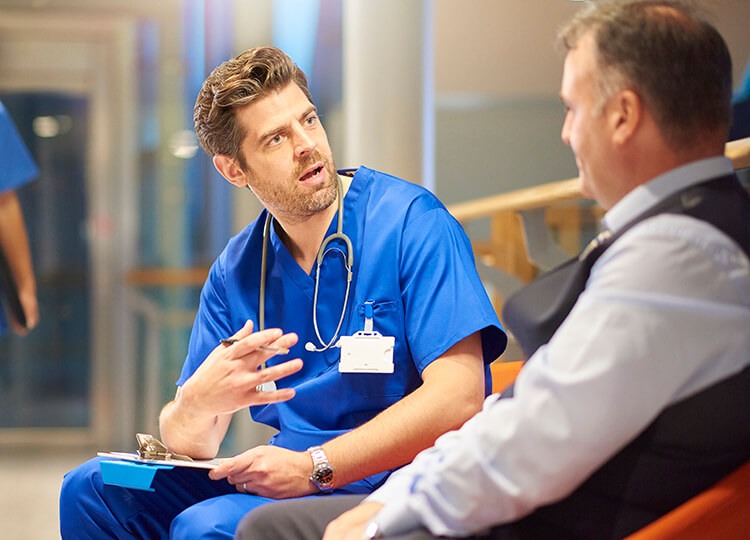 A medical professional talking with an older man.