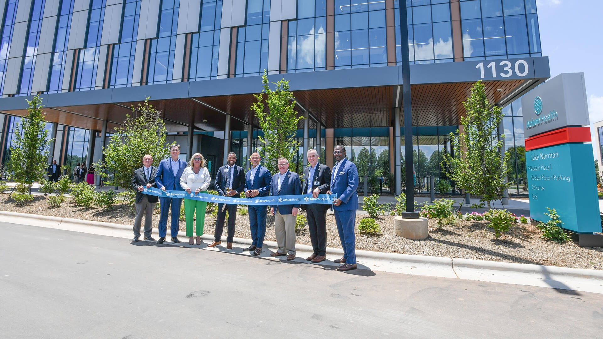 Atrium Health staff and executives stand with a ribbon in front of the new Lake Norman Hospital for a ribbon cutting.