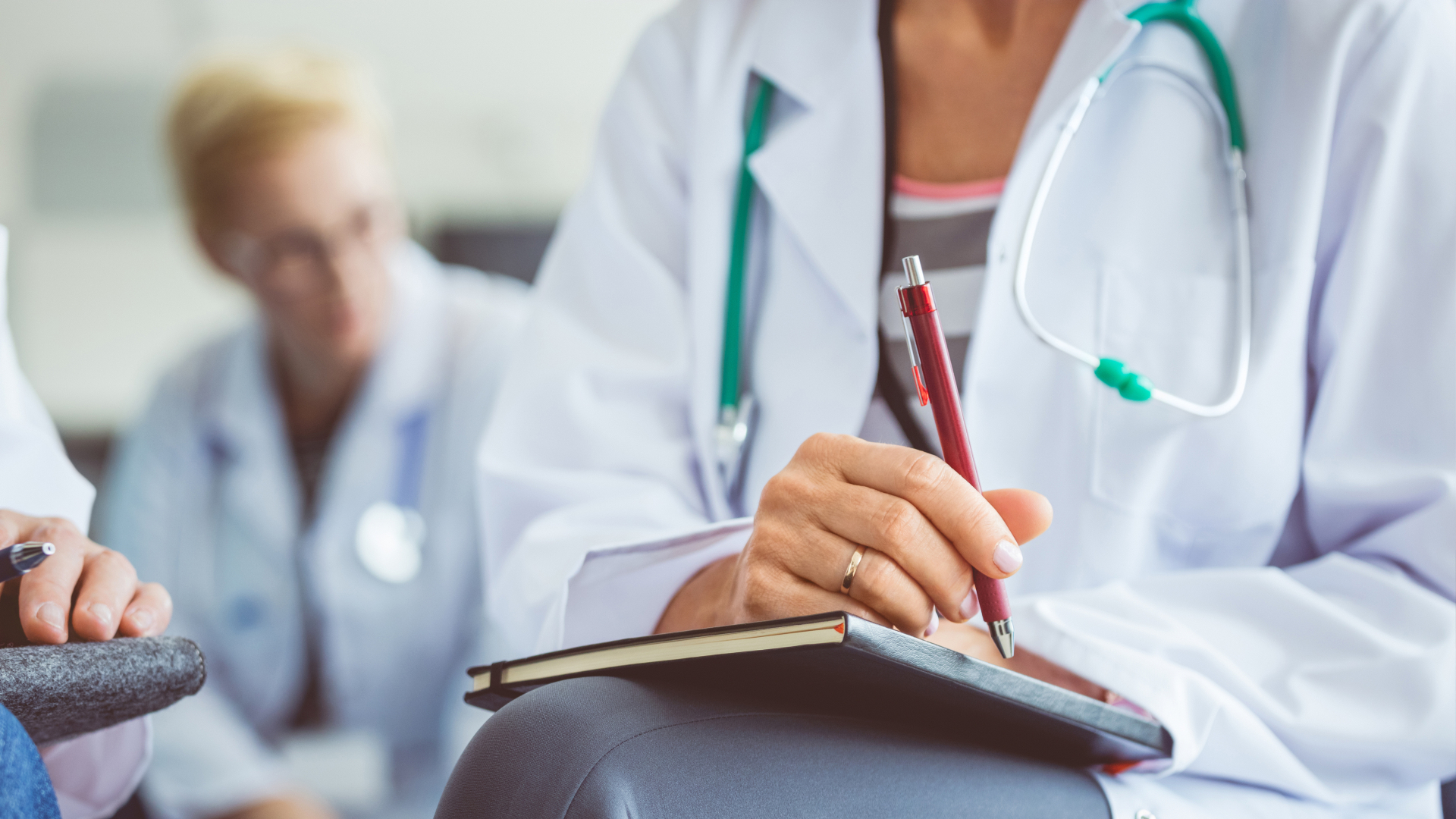 Medical professional taking notes with pen and paper