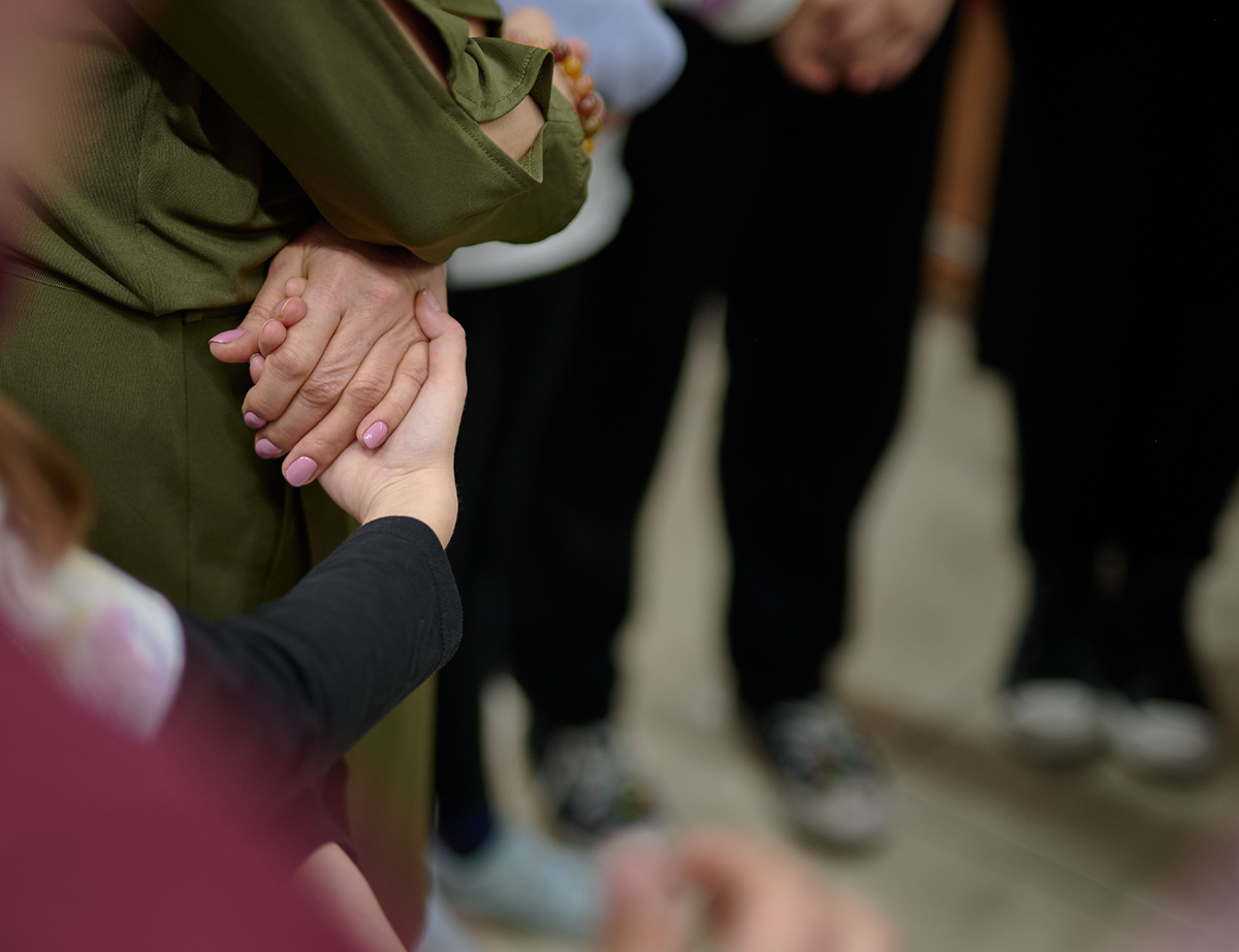 Close-up of a hand in a supporting gesture, surrounded by others, demonstrating support, unity, and care within a community
