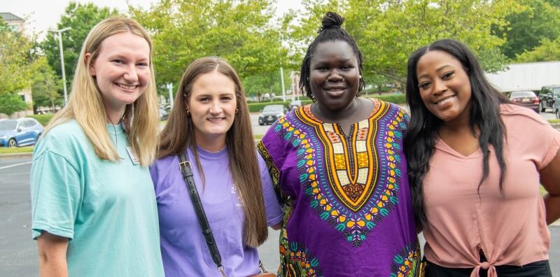 Four women posing for picture outside.