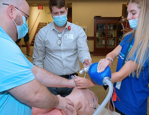 A group of respiratory therapy students practicing treatments on a dummy.