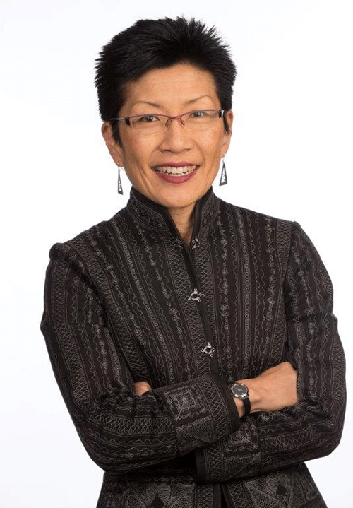 An woman with short hair and glasses looking at the camera and smiling.