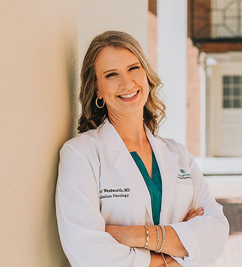 A woman with blonde hair wearing a medical jacket smiling at the camera.