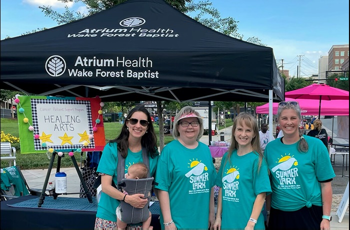 4 Women of the Cancer Patient Support Program team standing side by side wearing teal Summerlark shirts outside