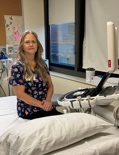 Cindy Brown sits next to an ultrasound machine.