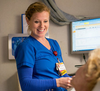 Mary Swaim, RN smiling at a patient. 
