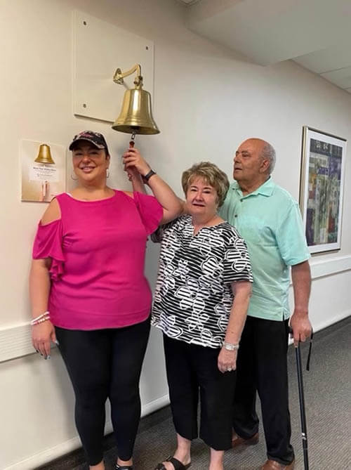 A woman ringing a bell with her family to signify she has finished chemotherapy.