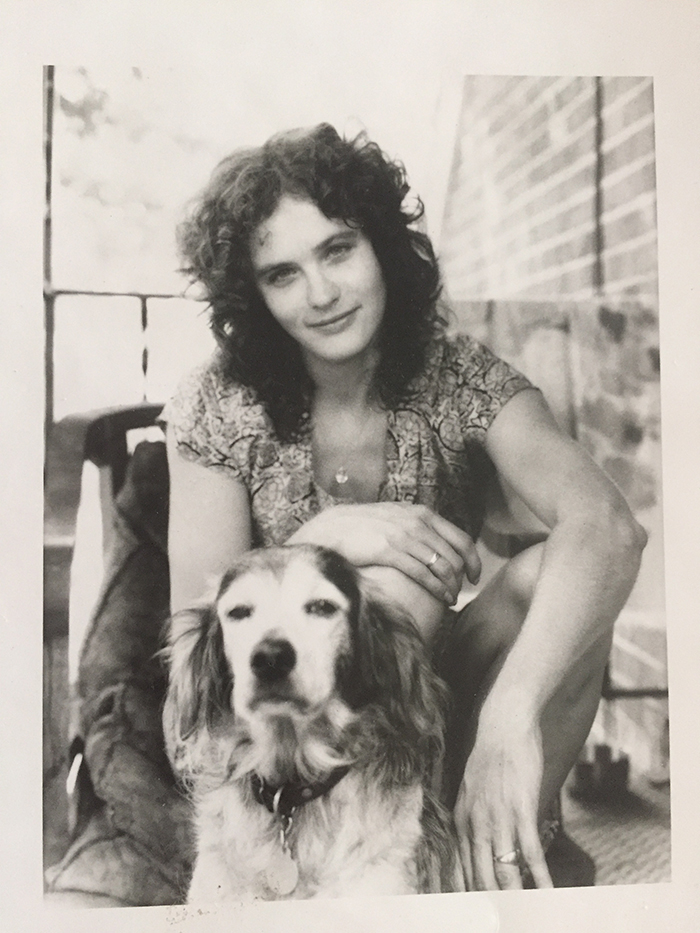 Black and white photo of young woman sitting on porch with dog